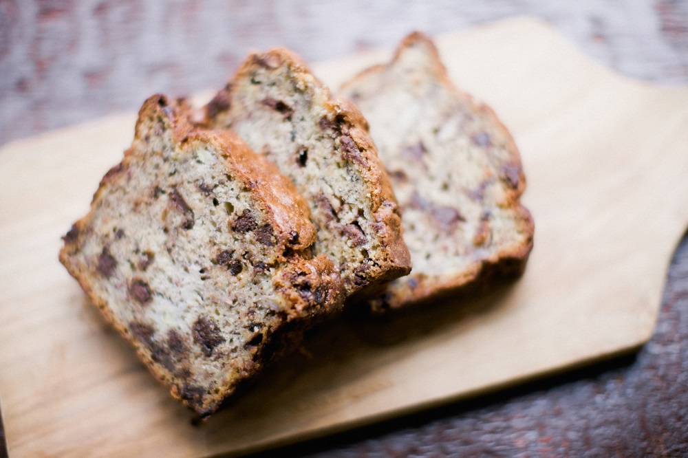 Chocolate chip banana bread on a wooden cutting board on a wooden table