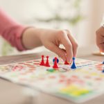Close up of hands moving objects around a game board.