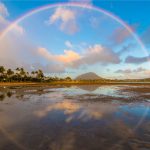 Full circle rainbow across tropical Hawaiian island bay with circle reflections in the ocean water